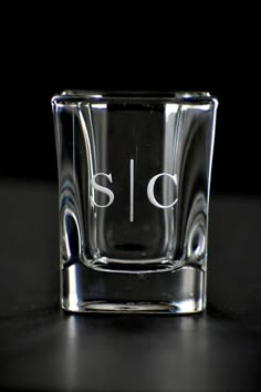 a shot glass with the word sic written in white ink on it, sitting on a black surface