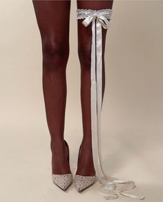 the legs of a woman in high heels with white lace on them and a ribbon tied around her ankles