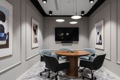 a conference room with chairs and a round table in front of a flat screen tv