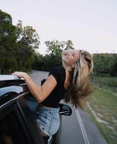 a woman is leaning out the window of a car and looking up at the sky