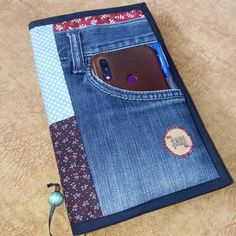 a cell phone is in the pocket of a blue jean case with a patchwork design