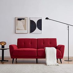 a red couch sitting on top of a hard wood floor next to a black table