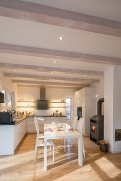 an open kitchen and dining room area with wood flooring, white walls and ceiling