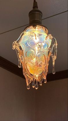 a glass light hanging from the ceiling in a room with a brown wall behind it