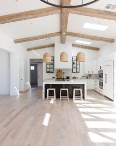 an open kitchen with white cabinets and wood flooring is pictured in this image, there are three stools on the island