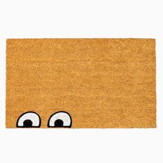 a yellow door mat with eyes drawn on the front and side, against a white background