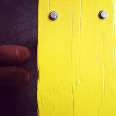 a person is holding onto a yellow piece of wood with two screws on it