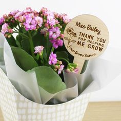 a bouquet of flowers with a wooden sign that says thank you for helping me grow