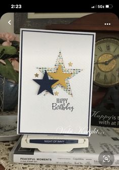 a birthday card with a star on it and a clock in the background next to some books