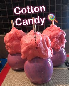 three purple cotton candy balls with lollipops in them sitting on a table