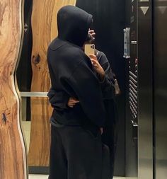 a person wearing a hoodie taking a selfie in front of a mirror with his cell phone