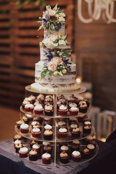 a tiered cake with cupcakes and flowers on it