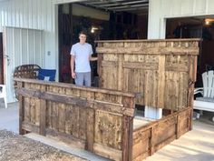 a man standing next to a bed made out of wooden slatted doors and windows