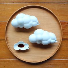 two white clouds sitting on top of a wooden plate