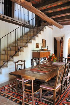 a dining room table and chairs in front of a stair case