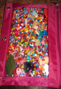 a pink bag filled with lots of different types of toys and beads on top of a wooden table