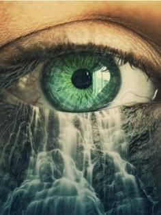 an eye with green eyes and waterfall in the background, as if it were looking at something