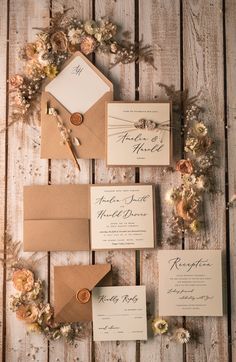 the wedding stationery is laid out on a wooden table with flowers and greenery