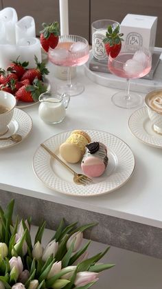 a table topped with plates and cups filled with desserts next to strawberries on top of each plate