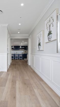 an empty room with hard wood floors and white paint on the walls, along with pictures hanging on the wall