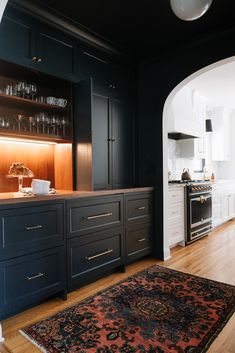 a kitchen with black cabinets and an area rug