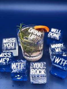 a drink with ice cubes and an orange slice on the rim, surrounded by words