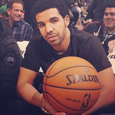 a man holding a basketball in his right hand while sitting next to other men on the sidelines