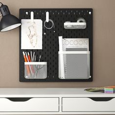 a black pegboard mounted to the side of a wall with office supplies on it