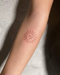 a woman's arm with a small sun tattoo on it