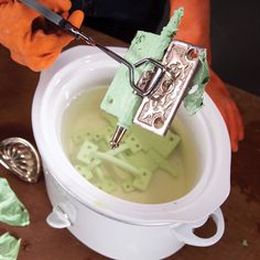 a person is using scissors to cut into something in a bucket with green liquid inside