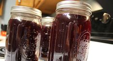 two jars filled with liquid sitting on top of a counter next to a stovetop