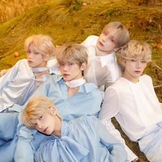 four young men laying on the ground in blue dresses and white collars, all looking at the camera