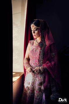 a woman in a bridal gown standing by a window