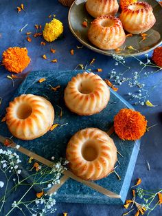 three glazed donuts on a blue plate with orange flowers and dried herbs in the background