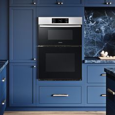 a black and silver oven in a blue kitchen with marble counter tops on the wall