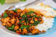 a white plate topped with chicken and spinach next to rice on top of a table