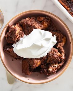 a bowl filled with cake and whipped cream on top of a marble counter next to a plate