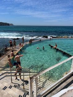 people are swimming in an outdoor pool next to the ocean