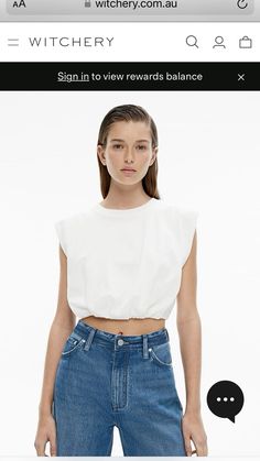 a woman in white crop top and jeans looking at the camera with her hand on her hip