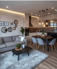 a living room filled with furniture next to a kitchen and dining room table on top of a hard wood floor