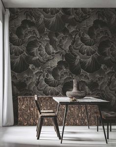 a dining room table with two chairs and a vase on top of it in front of a floral wallpaper