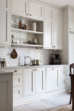 a kitchen with white cupboards and counters in the center, along with a dining room table