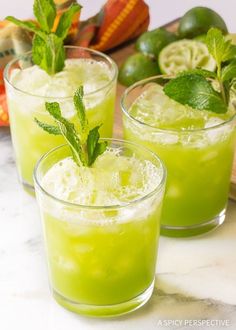 two glasses filled with limeade and mint garnish on top of a marble counter