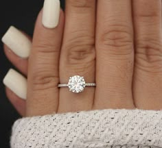 a woman's hand with a white manicured nails and a diamond ring