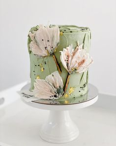 a green cake with flowers on it sitting on top of a white table next to an instagram post