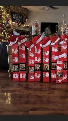 several red bags with white hand prints and santa hats on them sitting in front of a christmas tree