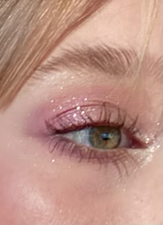 a woman's eye with pink glitter on the lashes and her eyes are closed