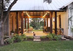 a covered porch with lights strung from the ceiling and sitting area on the grass outside