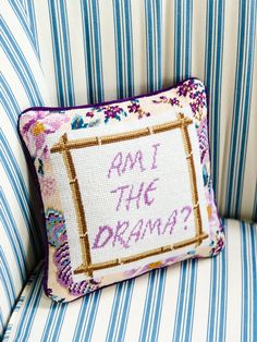 an embroidered pillow with the words am i the drama on it sitting on a striped chair