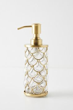 a glass soap dispenser on a white surface with gold trimmings